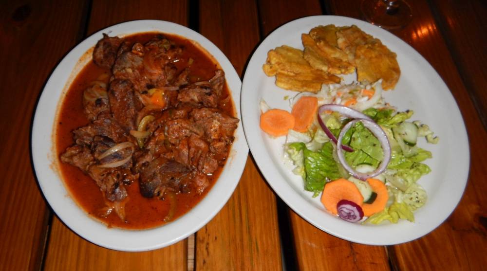 Typical meal in Haiti consisting of goat in Kreyol sauce, fried plantains, and salad